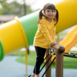asian little girl enjoys playing in a children playground, outdo