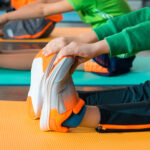 cropped view of children stretching on fitness mats in sports center, panoramic shot