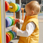 cute baby boy playing on the playground with colorful abacus. children developments, kids education, baby learning.