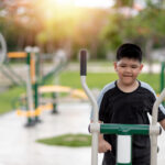 fat boy trains on fitness equipment in the park
