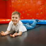 jouful little boy luing on trampoline, playground