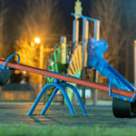 seesaw swing in preschool yard with soft rubber flooring at night.