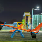 seesaw swing in preschool yard with soft rubber flooring at nigh