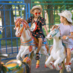 the sisters ride in a circle on carousel sitting on colored horses